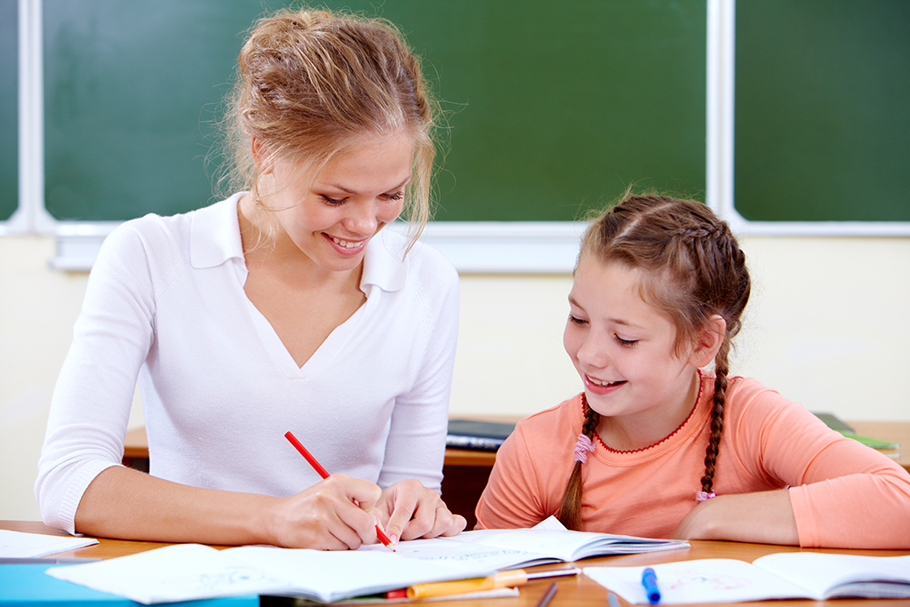 Portrait of young teacher showing her pupil how to draw at lesson